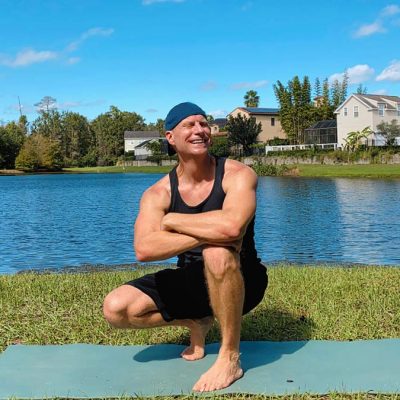 Photo of Sean Vigue on a Yoga Mat in front of a lake on a sunny day